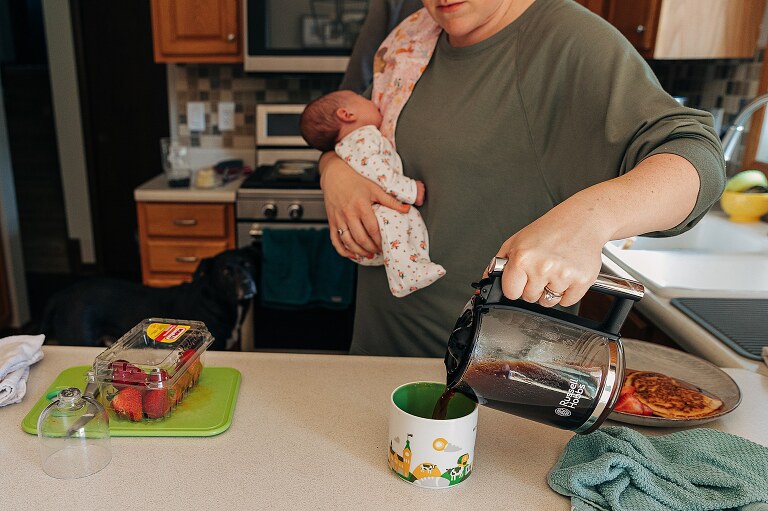 mom holds newborn and pours coffee with the other hand