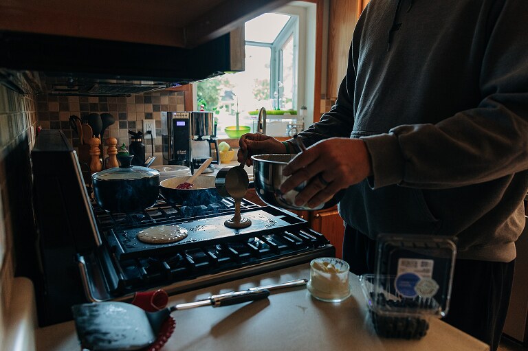 Man pours pancake mix on the hot griddle