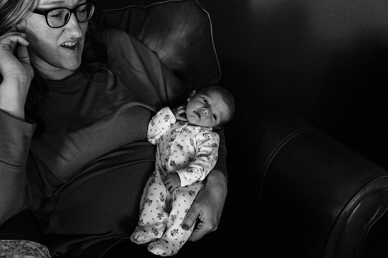 black and white. mom and newborn share same gesture-hand to ear--on a quiet summer morning