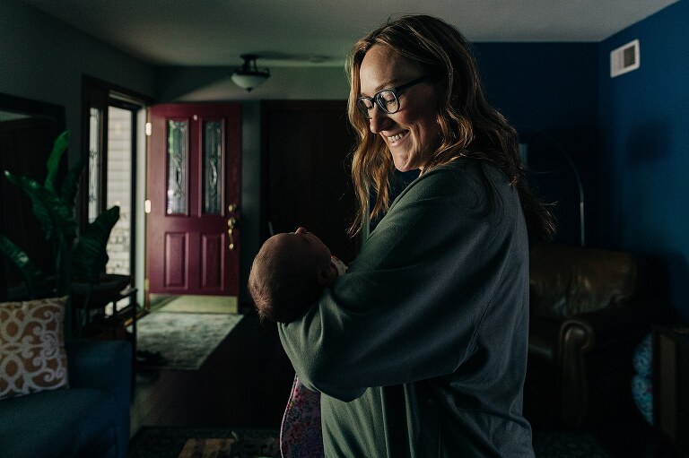 new mom smiles at her newborn on a quiet summer morning