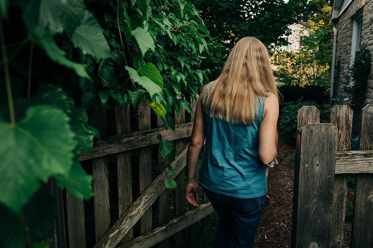 Woman with long blond hair walks through an open wooden gate on summer nights