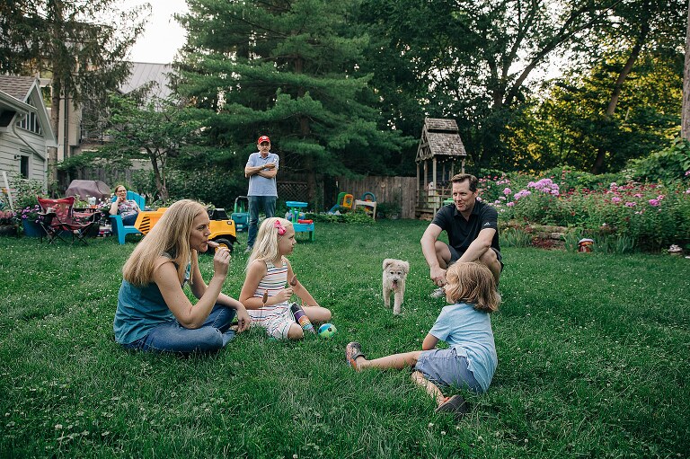 Family of 6 and their dog sit in the grass, smiling and talking, while eating FudgePop popsicles 