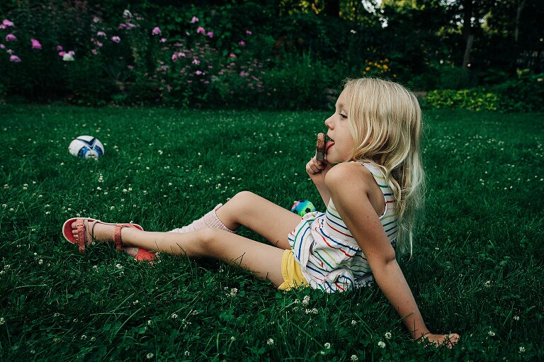 young child eats a FudgePop popsicle in the grass on summer nights 