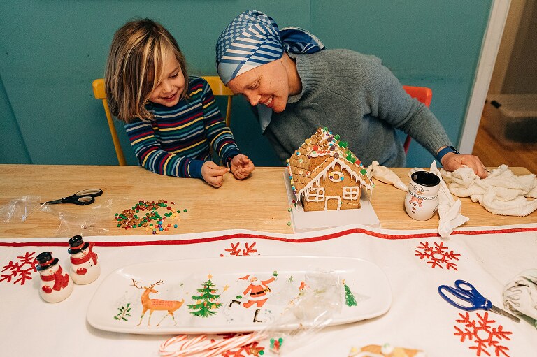 mom and son examine their gingerbread house that they made for chistmasy photos 