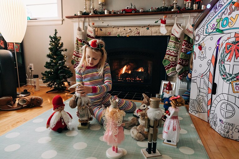 young girl plays with christmassy nutcrackers in front of photos 
