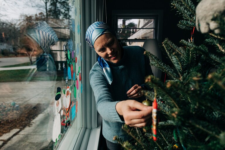 mom hangs christmasy photo ornaments on the tree