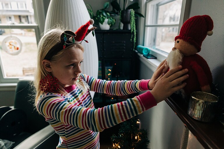 girl examining a santa on a mantle that looks christmassy