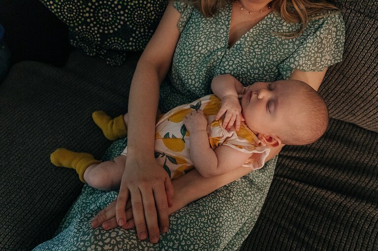 baby sleeps in mother's arms in a home from which they will be moving on