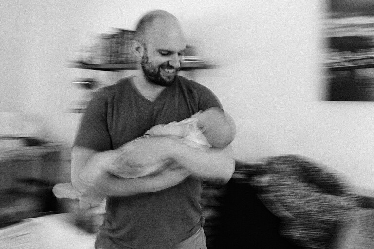 dad holds sleeping baby, motion blur visible as dad sways to hold her