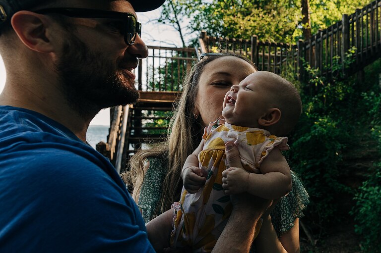 man takes smiling baby from woman at a park from which they will be moving on from