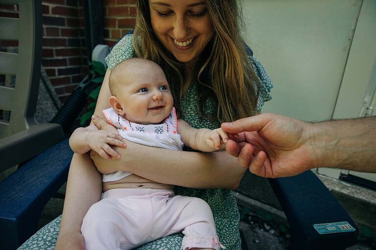 mom smiles at baby while dad reaches hand in and baby smiling off camera at him 