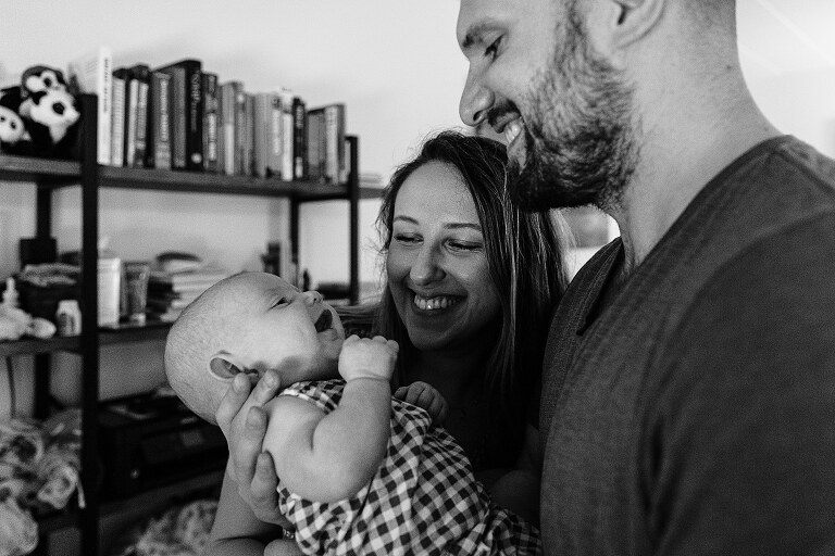 mom and dad and baby all close and smiling big
