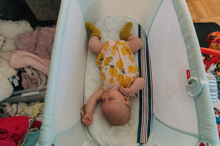sleeping baby in a basinet with packing for moving on all around