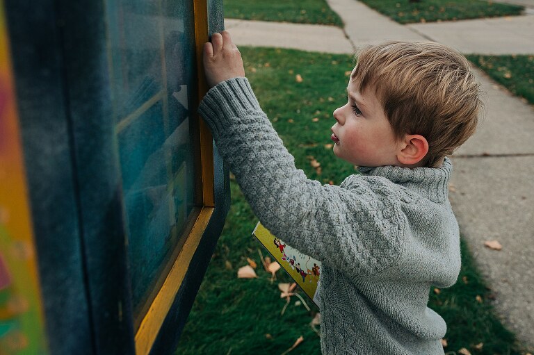 young child opens door to a Little Free Library