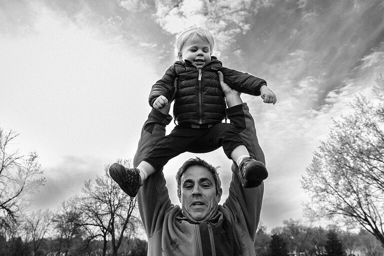 dad pulls son over his head to put on his shoulders 