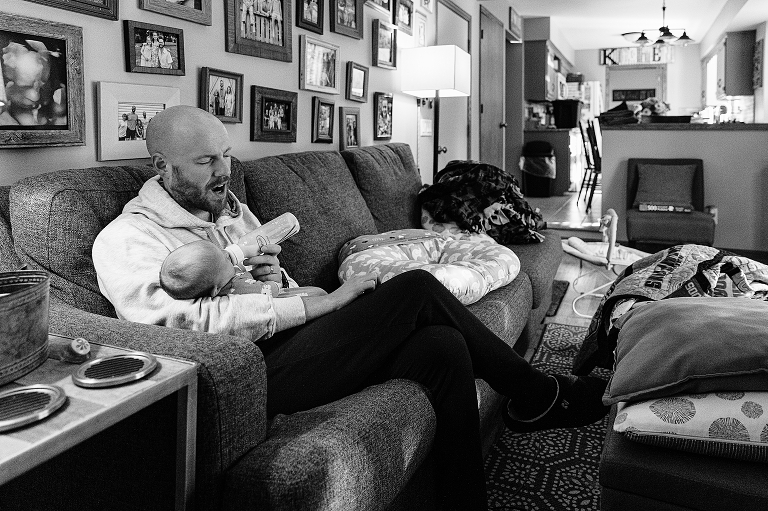 Black and white, father feeds newborn baby from bottle, life with newborn.