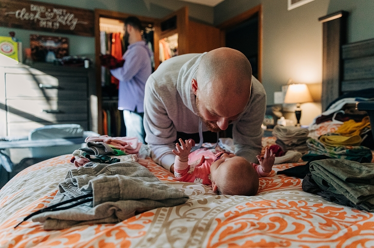 One father puts away laundry while the other cares for the newborn. 