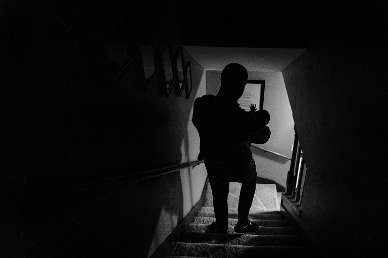 Father brings newborn downstairs in his arms 