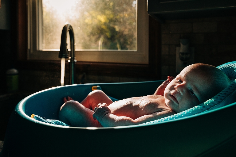 Newborn baby lies in aqua cradle after bath