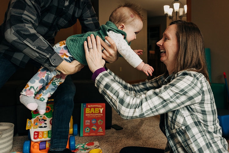 mothers smiles as toddler daughter is placed in her arms 