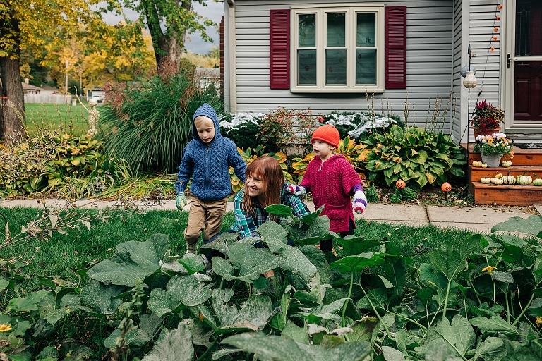 mothers garden with two children, picking pumpkins, smiling