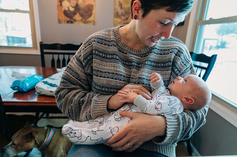 mother holds newborn baby in her arms in the kitchen 