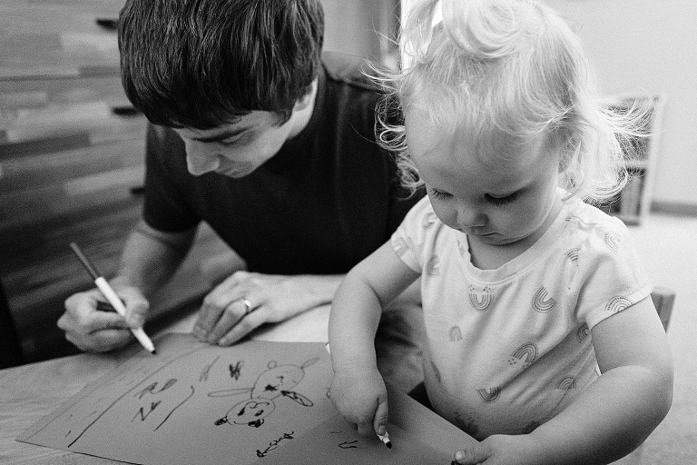Dad and toddler daughter make art together. 
