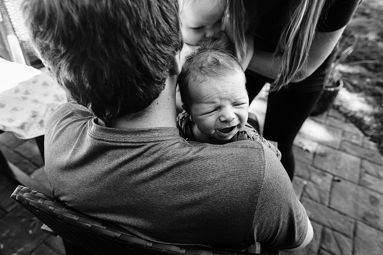 Newborn cries while Dad holds and older sister comes to comfort