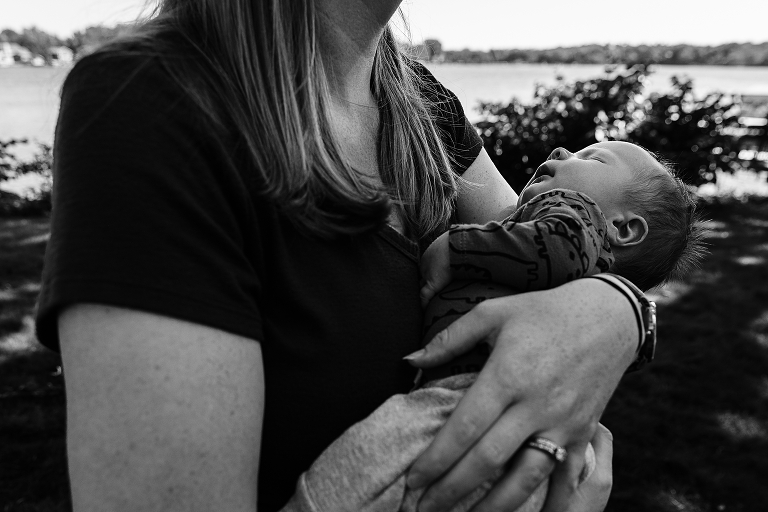 Mom cradles newborn next to the lake