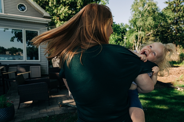 Mom playfully spins toddler daughter and hair and expressions show movement and happiness 