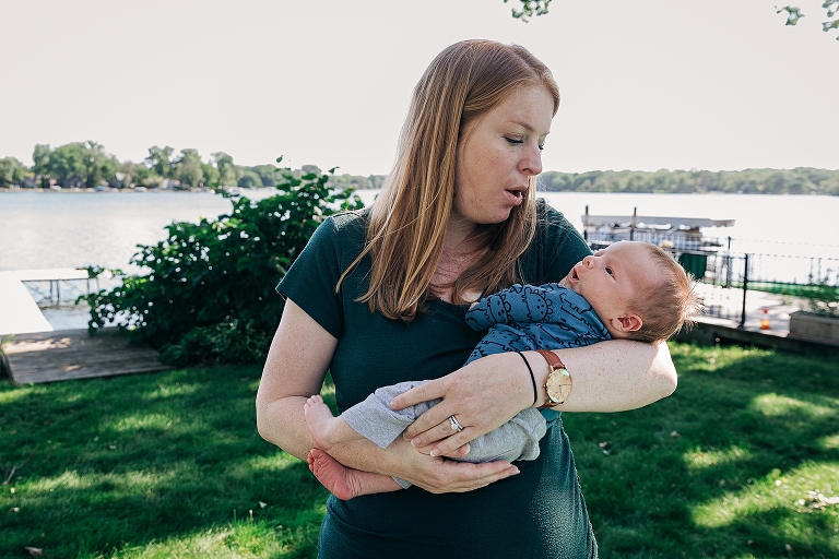 Mom and newborn share the same surprised expression by the lake