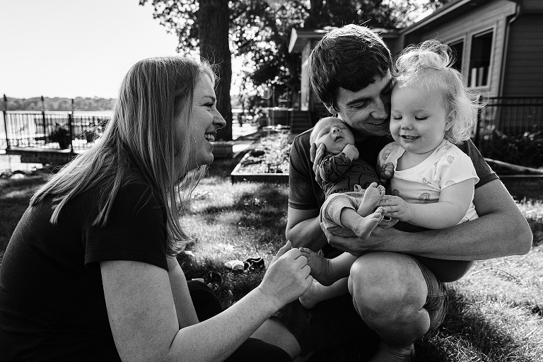 Family of four smile and connect with each other outside next to the lake