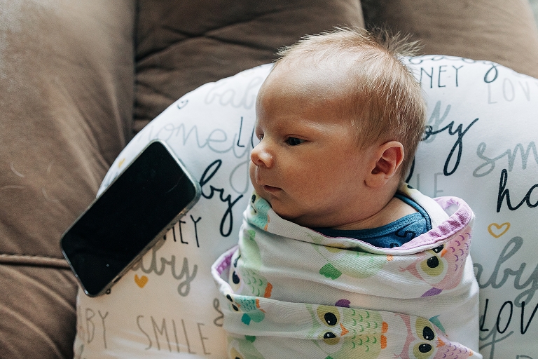 swaddled newborn lies awake on a Boppy listening to white noise 
