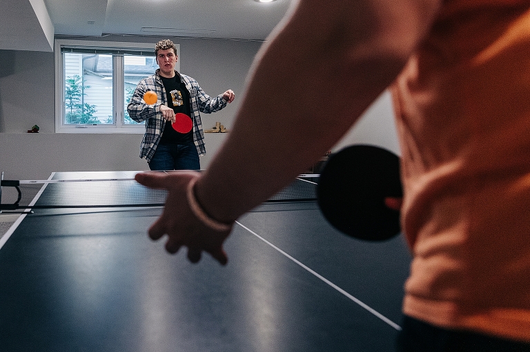 Eldest and youngest brother play ping pong with youngest brother in foreground