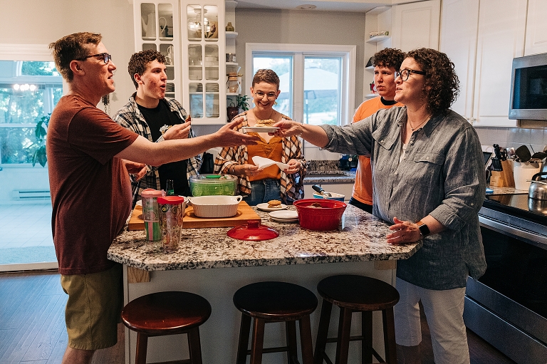 Family laugh together and toast their desserts at their kitchen island "all together now"