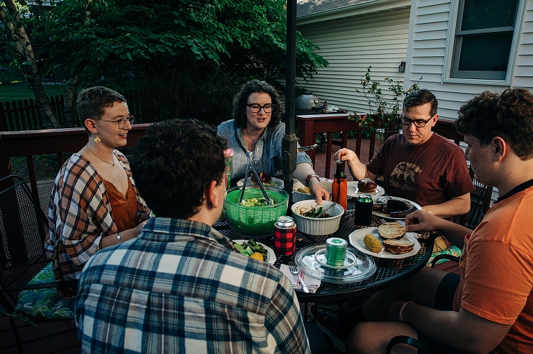Family converse together during their meal, two adult sons, one adult daughter, a mother, and father. 
