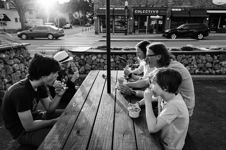 Black and white: family enjoys their ice cream with dog begging in the background