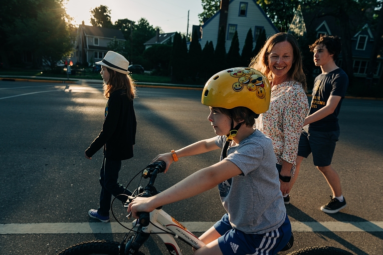 Family walks/bikes towards home in the late afternoon sun