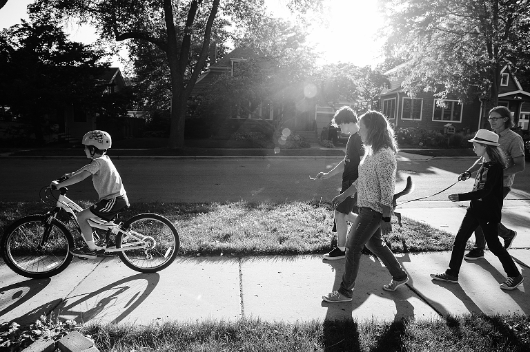 Black and white: whole family goes outside for a walk, youngest son rides his bike