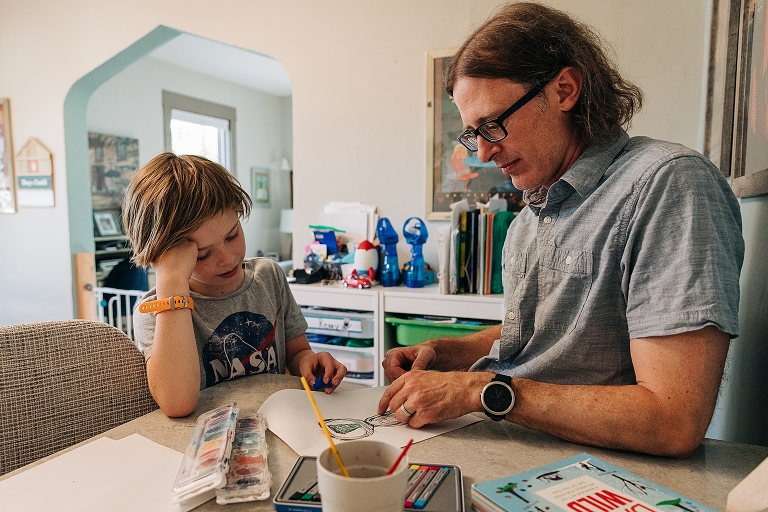 Youngest son draws with father during late spring at home
