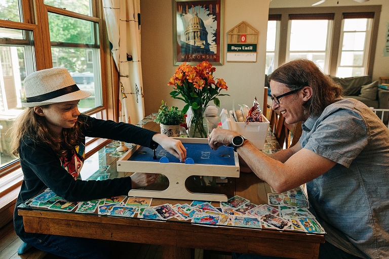 Middle son plays tabletop Klask with his father in the dining room during a late spring at home