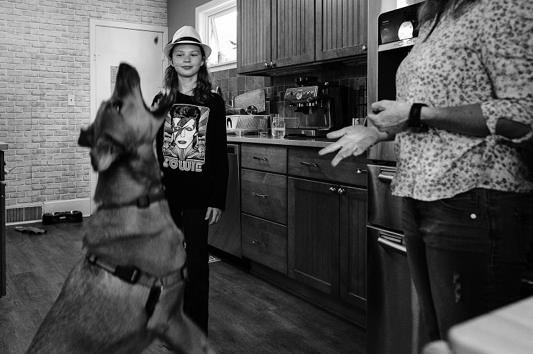 Black and white: mother talks with young son while family german shepard catches treat mid air