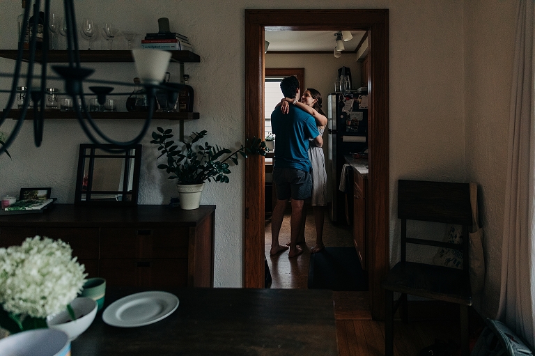 Mother and father embrace with the dining room of the home in the foreground
