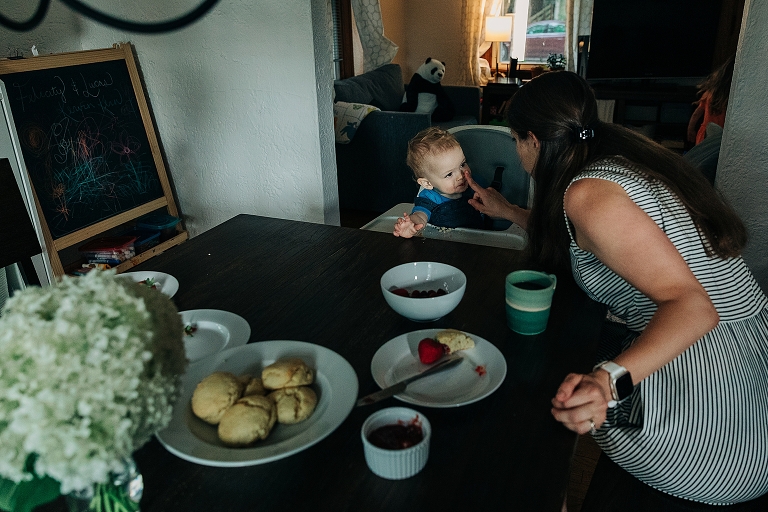 Mother playfully touches young son's nose at breakfast in home