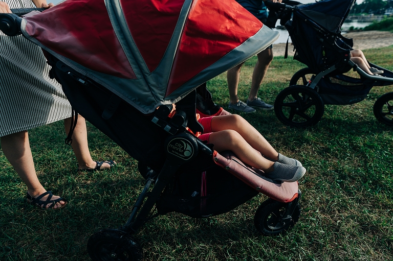 Mother pushes child in red stroller at Tenney Park.