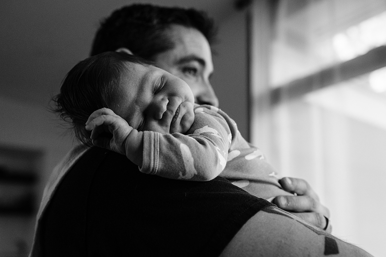 black and white father holds sleeping newborn son