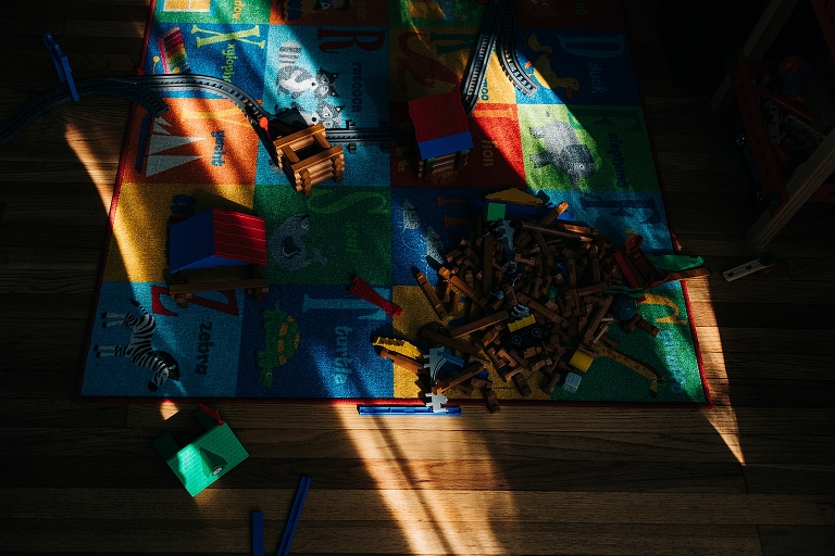 lincoln logs and other toys lay strewn on play rug 
