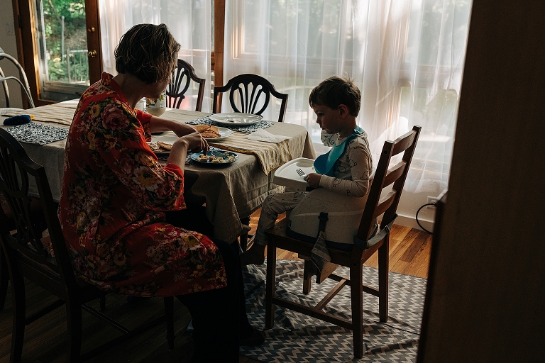 mother cuts food for young child at breakfast table 