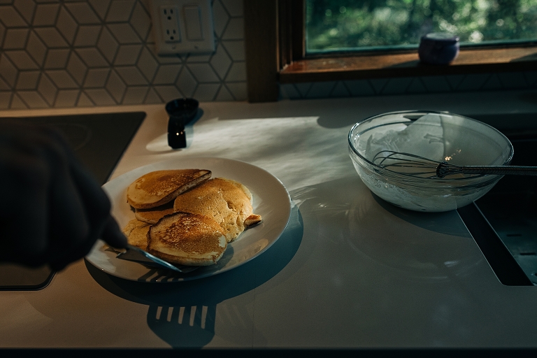 person reaches to grab pancake with spatula in the kitchen 