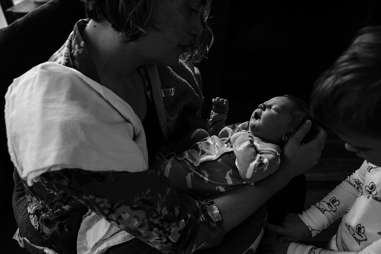black and white mother watches newborn sleep in her arms 
